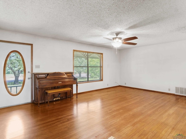 interior space featuring a textured ceiling, light wood-type flooring, and ceiling fan