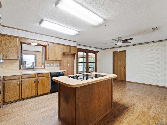 kitchen with sink, black appliances, a textured ceiling, and light wood-type flooring