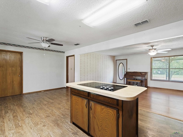 kitchen with hardwood / wood-style floors, a textured ceiling, and black electric stovetop