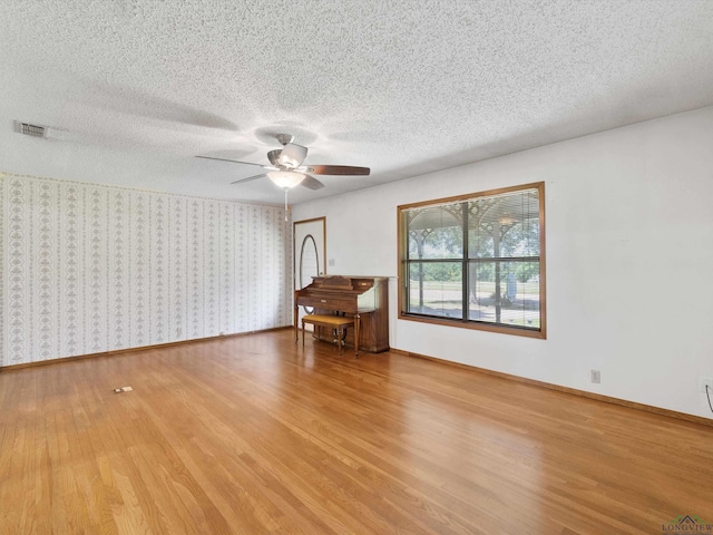 empty room featuring a textured ceiling, light hardwood / wood-style floors, and ceiling fan