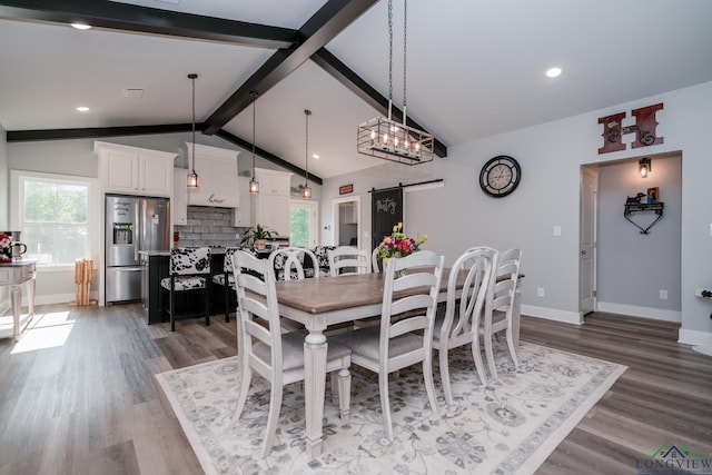 dining space featuring a barn door, lofted ceiling with beams, and hardwood / wood-style flooring