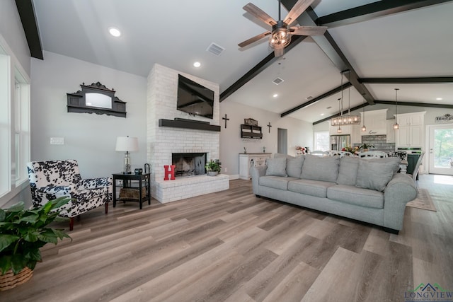 living room featuring vaulted ceiling with beams, ceiling fan, wood-type flooring, and a wealth of natural light