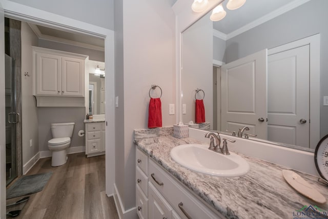 bathroom featuring vanity, toilet, ornamental molding, walk in shower, and wood-type flooring