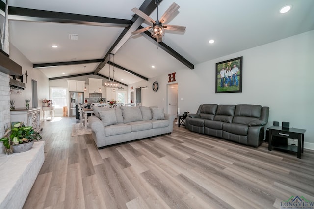 living room featuring ceiling fan with notable chandelier, vaulted ceiling with beams, and light hardwood / wood-style floors