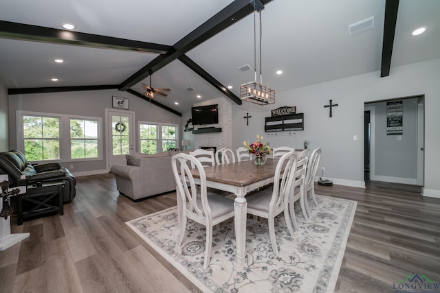 dining space featuring vaulted ceiling with beams, ceiling fan, hardwood / wood-style flooring, and a brick fireplace