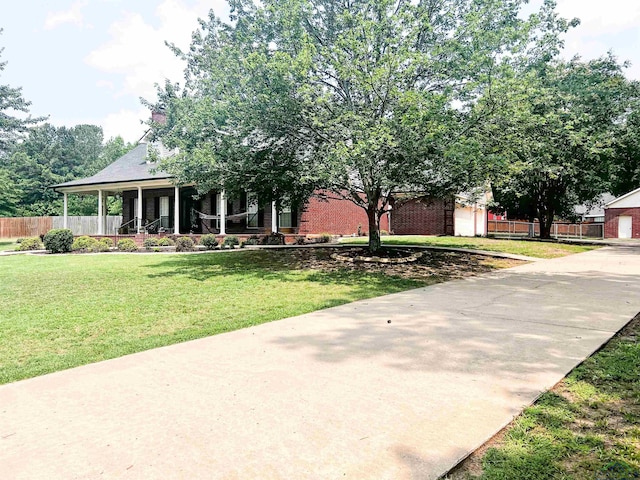 view of front of property featuring covered porch, brick siding, a front yard, and fence