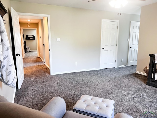 living area featuring baseboards, dark carpet, and ceiling fan