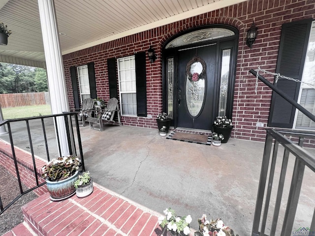 doorway to property with covered porch and brick siding