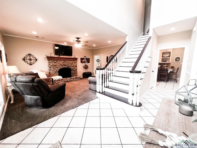 living area featuring a fireplace, a ceiling fan, stairway, tile patterned floors, and crown molding