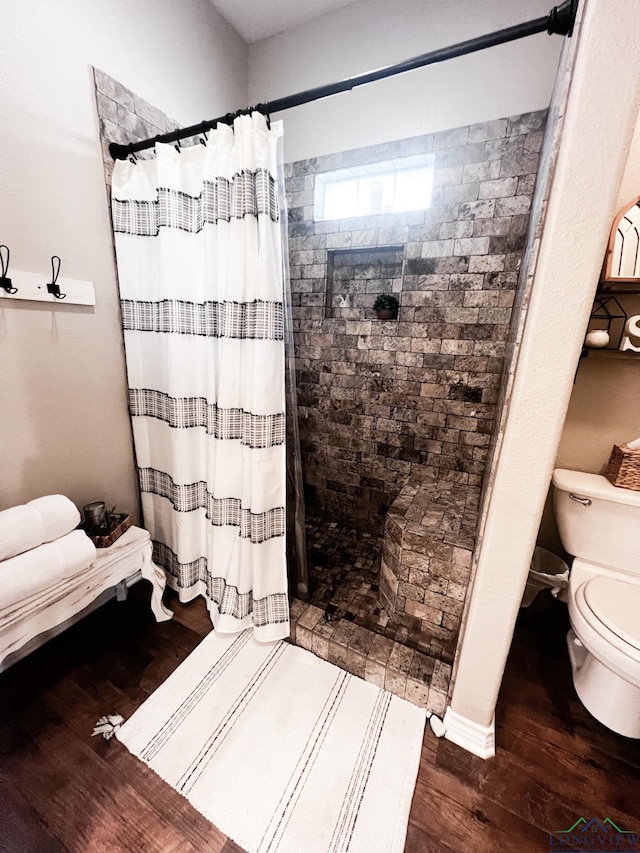 full bath featuring a tile shower, toilet, and wood finished floors