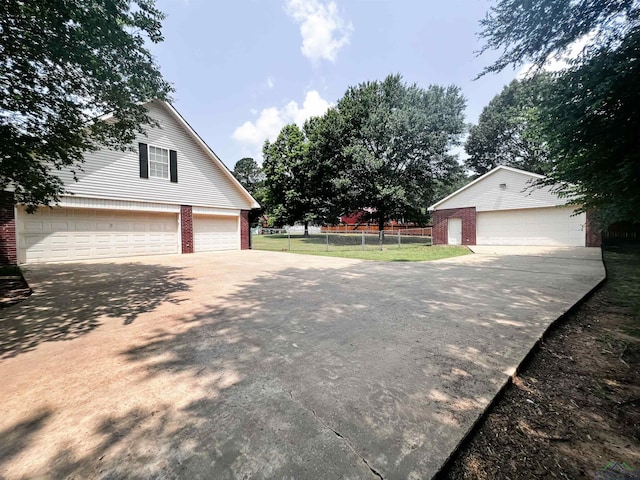 exterior space with a detached garage, fence, and brick siding