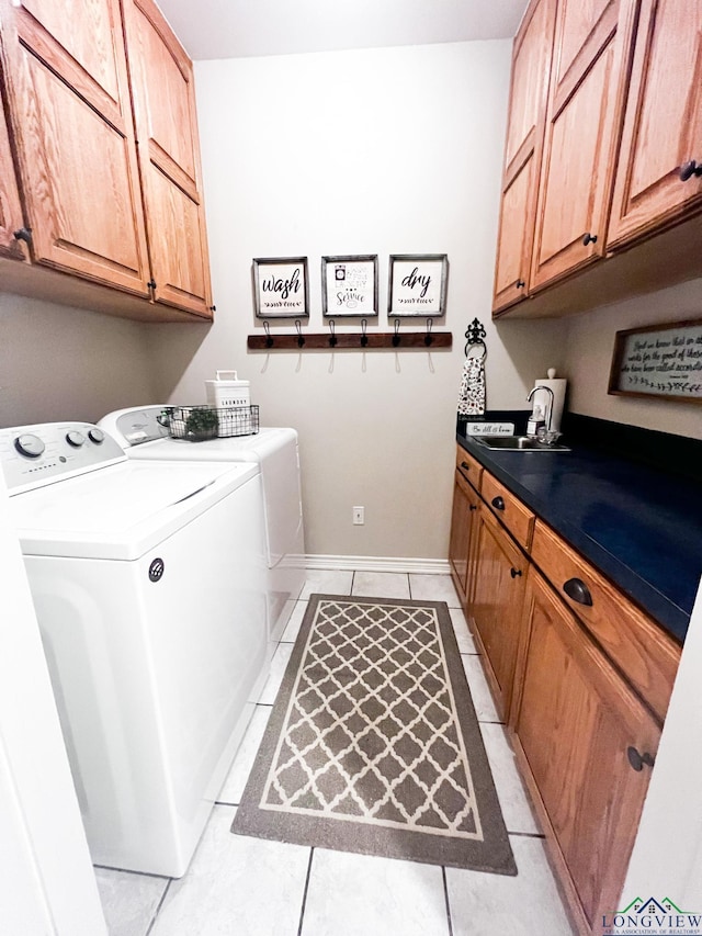 washroom featuring cabinet space, light tile patterned flooring, a sink, separate washer and dryer, and baseboards