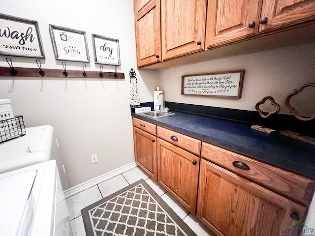 washroom featuring cabinet space, baseboards, washing machine and clothes dryer, a sink, and light tile patterned flooring