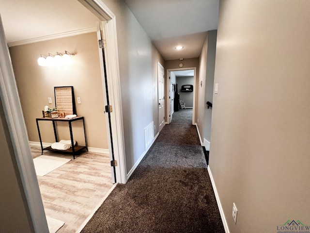 hallway with carpet floors, visible vents, and baseboards