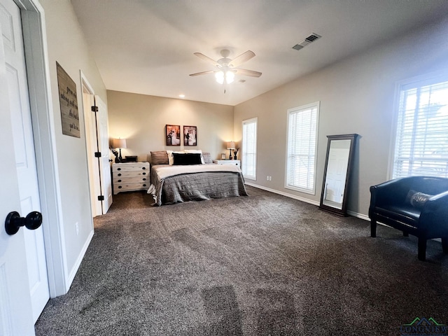 bedroom with ceiling fan, dark carpet, visible vents, and baseboards