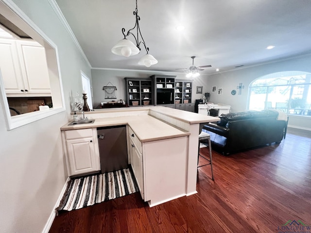 kitchen featuring dishwashing machine, a peninsula, dark wood-style flooring, white cabinetry, and a kitchen breakfast bar