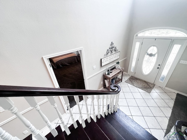 entryway with light tile patterned floors, stairway, and baseboards