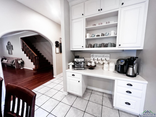 bar with stairway, baseboards, arched walkways, and light tile patterned flooring