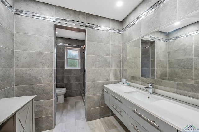 full bathroom with a shower stall, toilet, tile walls, and vanity