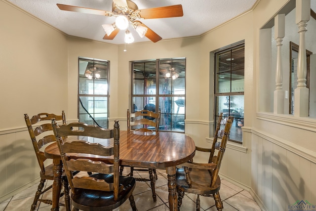 dining room featuring wainscoting, a textured ceiling, and ornamental molding