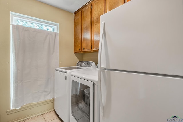 washroom featuring light tile patterned flooring, cabinet space, and washer and clothes dryer