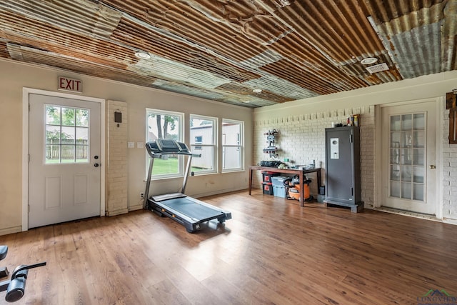 workout area featuring wood finished floors and brick wall