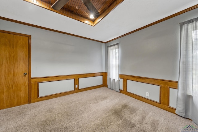 spare room featuring a ceiling fan, wainscoting, ornamental molding, light carpet, and wooden ceiling