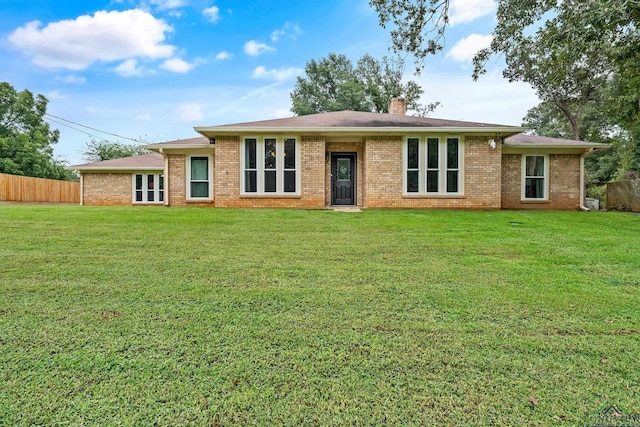 ranch-style house featuring a front lawn, fence, and a chimney