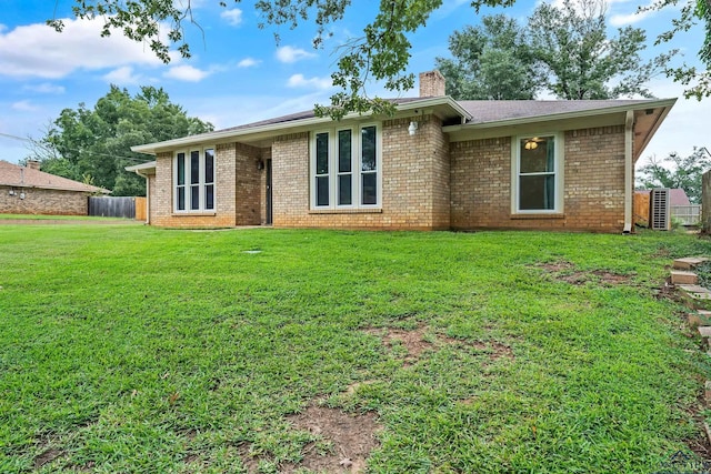 view of front of house featuring a front lawn, fence, brick siding, and a chimney