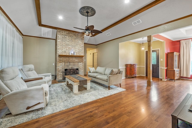 living room with visible vents, ornamental molding, a fireplace, and wood finished floors