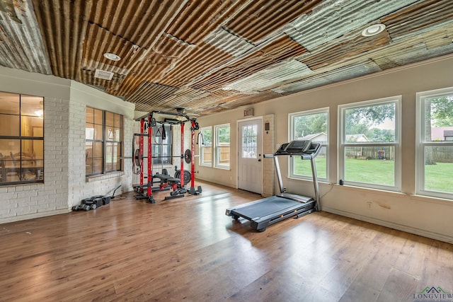 workout room featuring hardwood / wood-style floors and brick wall