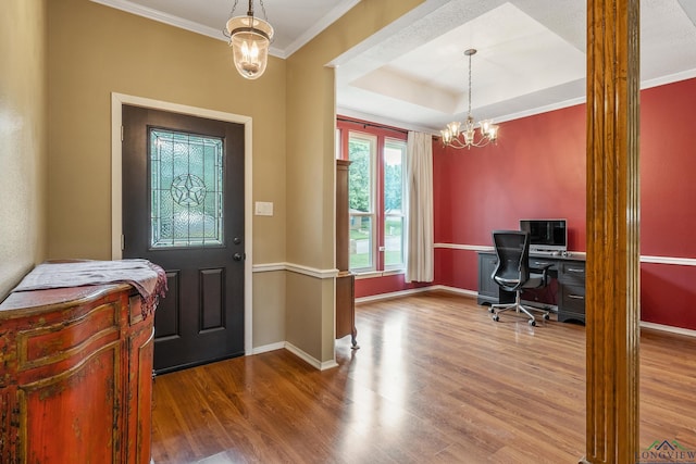 foyer entrance with crown molding, wood finished floors, baseboards, and a chandelier