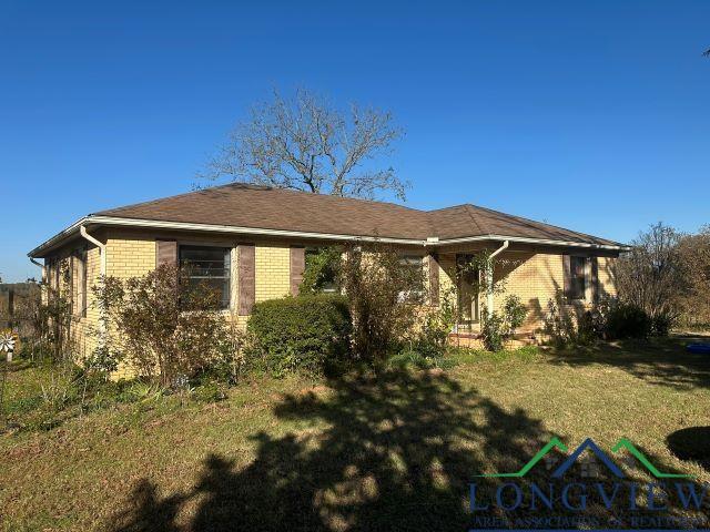 729 Rosehill Rd, Timpson, TX 75975 - view of home's exterior with brick siding and a lawn