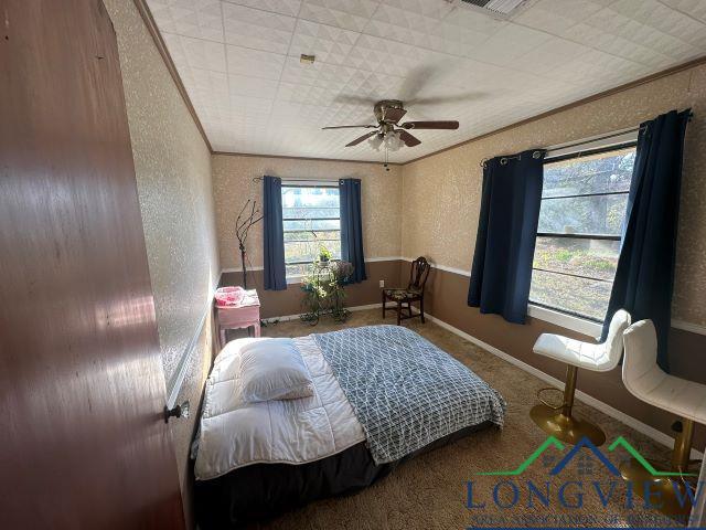 729 Rosehill Rd, Timpson, TX 75975 - bedroom with a textured wall, crown molding, a ceiling fan, and carpet