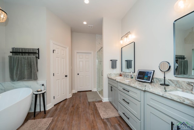 4523 Lone Oak Ln, Longview, TX 75605 - full bathroom with double vanity, a stall shower, a soaking tub, recessed lighting, and wood finished floors