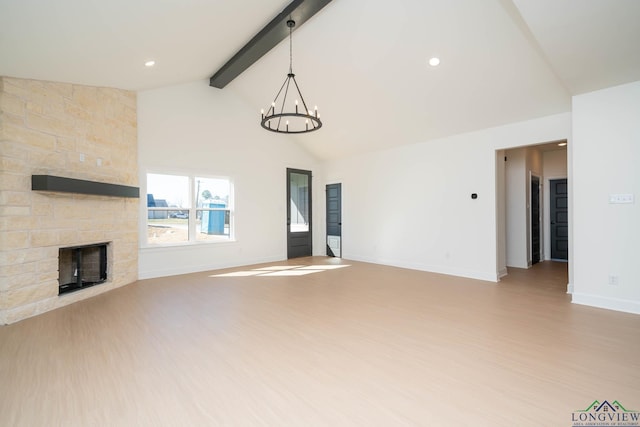 unfurnished living room with an inviting chandelier, a stone fireplace, light wood-type flooring, beamed ceiling, and baseboards