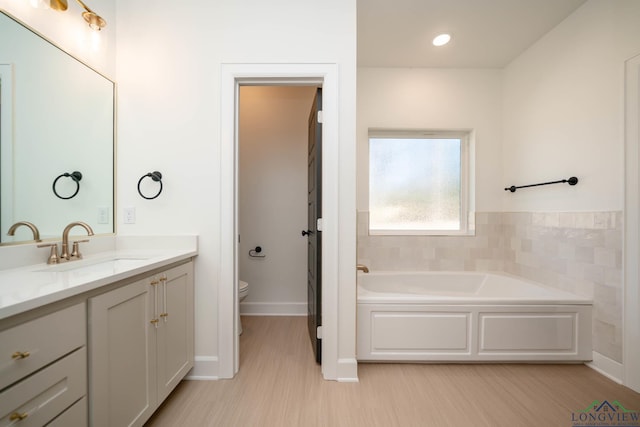 full bath featuring a bath, vanity, and toilet