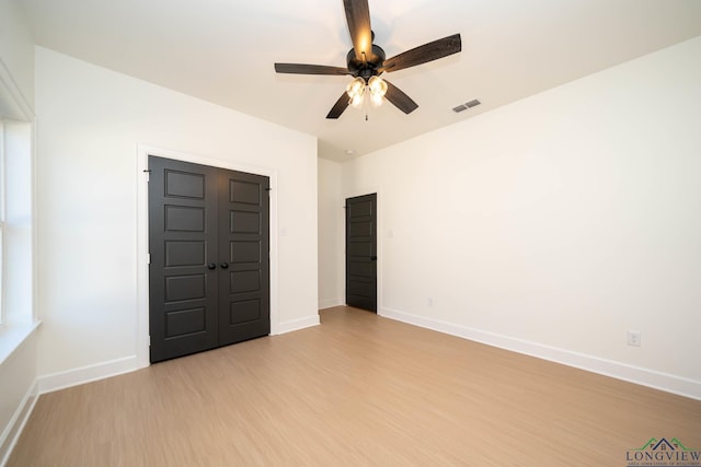 unfurnished bedroom featuring light wood-style floors, visible vents, baseboards, and a ceiling fan