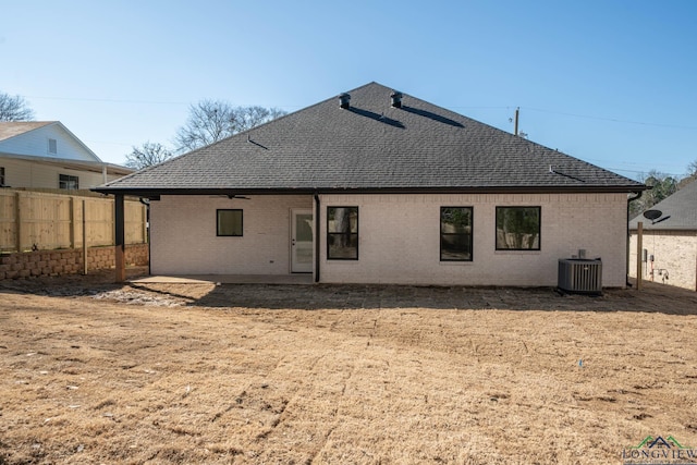 back of property featuring a shingled roof, fence, central AC, and brick siding