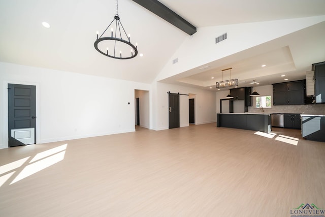 unfurnished living room with beam ceiling, visible vents, a barn door, light wood-style floors, and baseboards