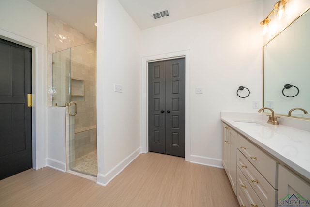 bathroom with baseboards, visible vents, wood finished floors, vanity, and a shower stall