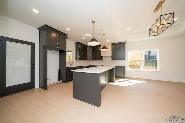 kitchen with recessed lighting, a kitchen island, light countertops, light wood-type flooring, and backsplash