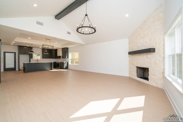 unfurnished living room featuring light wood-type flooring, visible vents, a fireplace, and an inviting chandelier