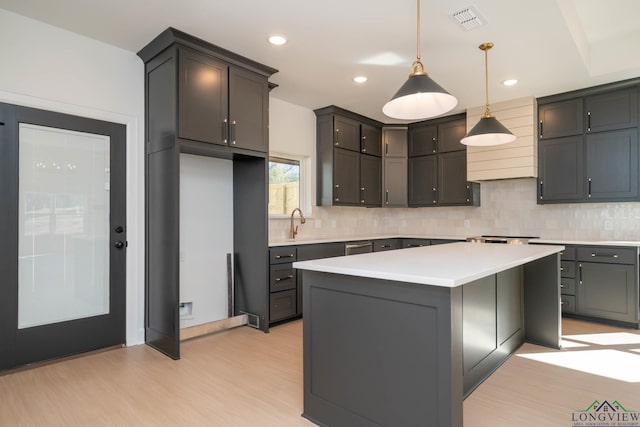 kitchen featuring visible vents, light wood-style floors, light countertops, tasteful backsplash, and decorative light fixtures