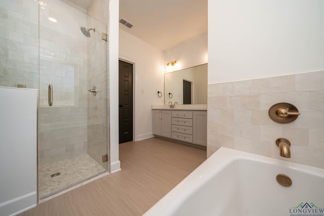 full bath with a washtub, visible vents, a shower stall, vanity, and wood finished floors