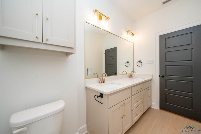 full bath featuring double vanity, wood finished floors, a sink, and toilet