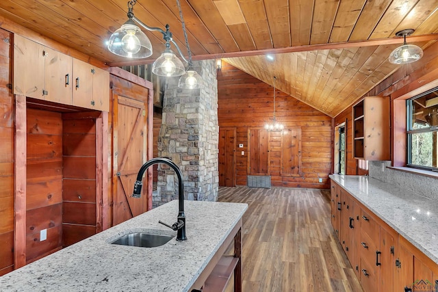 kitchen with light stone counters, sink, decorative light fixtures, and wooden ceiling