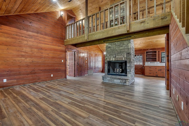 unfurnished living room with dark wood-type flooring, wood ceiling, a stone fireplace, and high vaulted ceiling