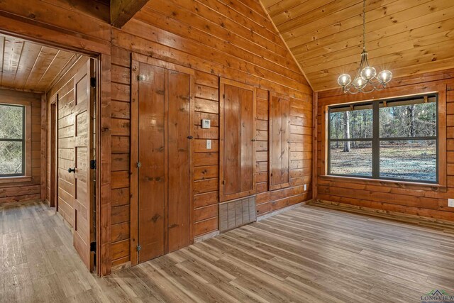 interior space with light wood-type flooring, lofted ceiling, wood ceiling, and wooden walls