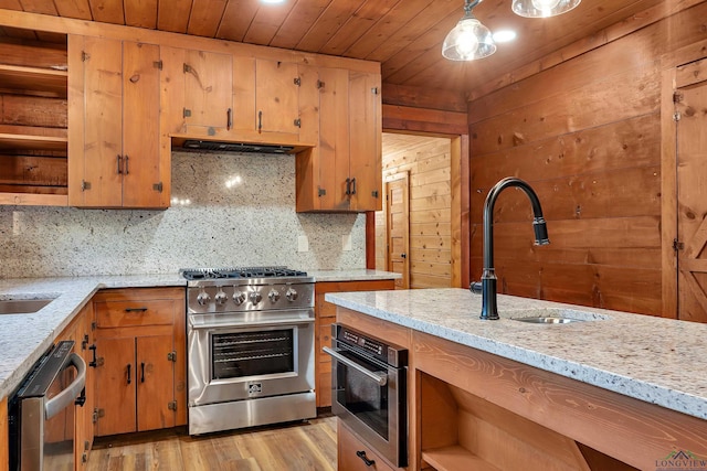 kitchen featuring appliances with stainless steel finishes, tasteful backsplash, light stone counters, and sink